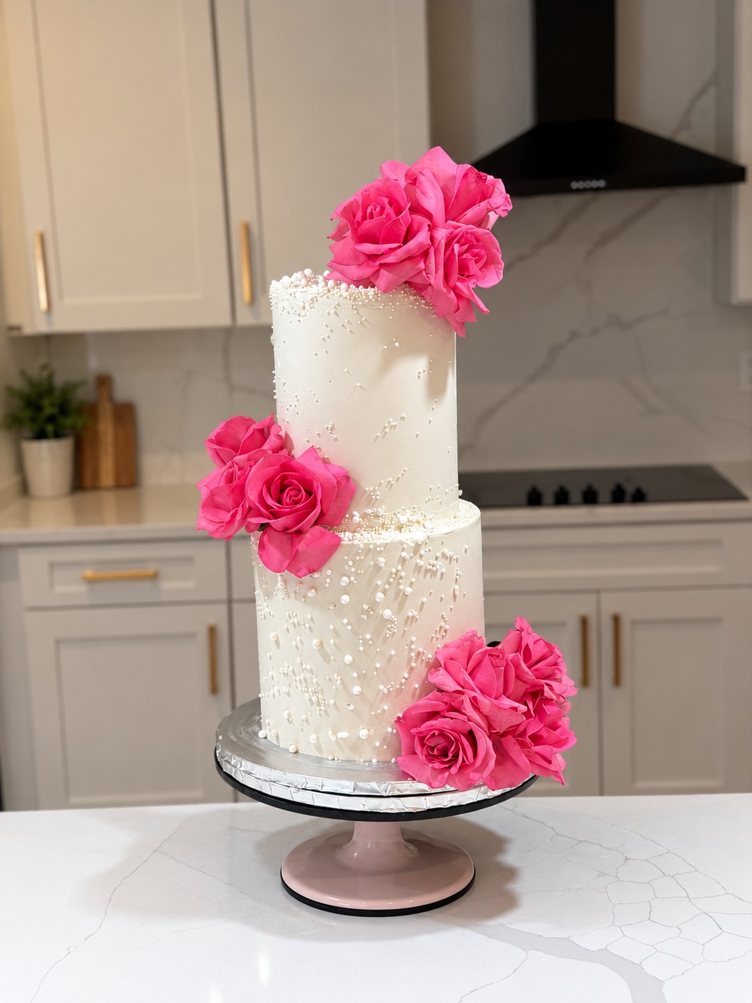 White tiered cake with vivid pink roses and pearl details
