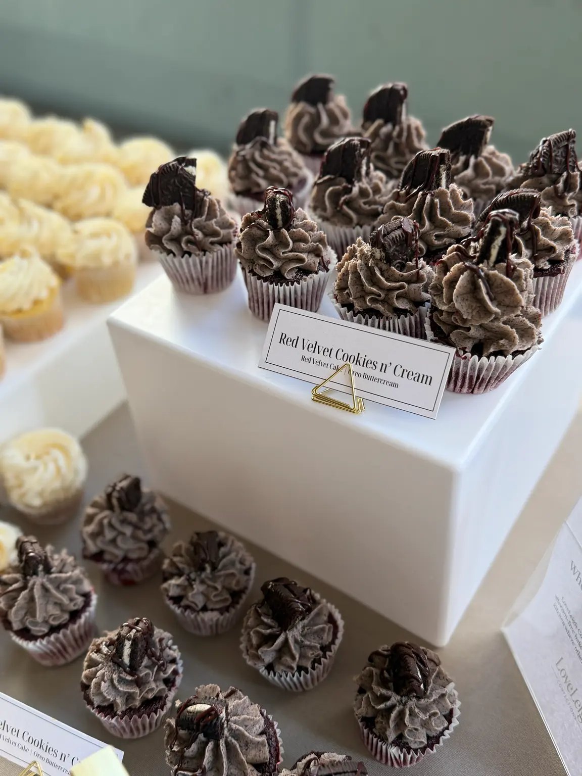 Red Velvet Cookies and Cream cupcakes displayed beside vanilla cupcakes