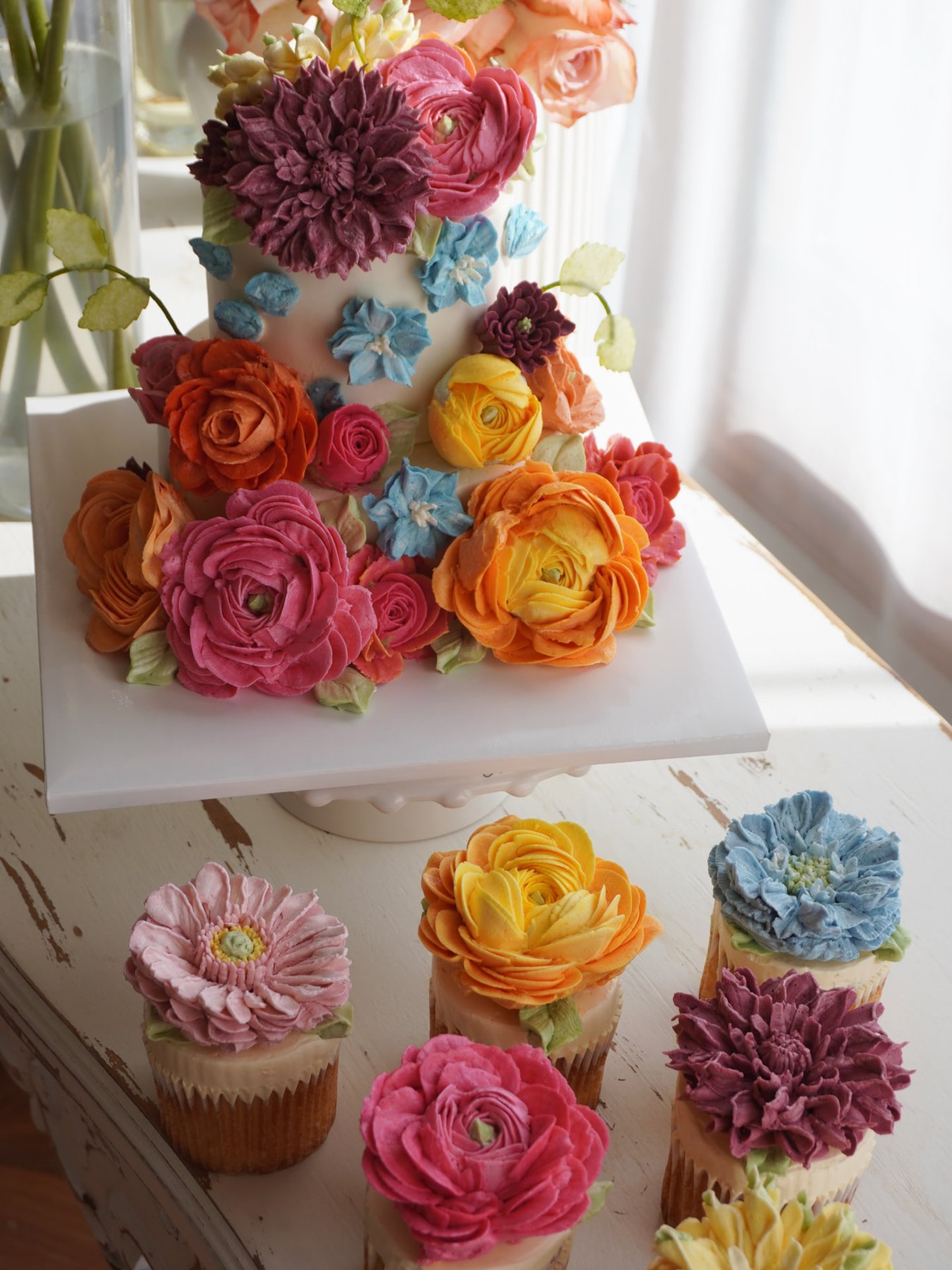 Colorful buttercream flower cake with matching floral cupcakes