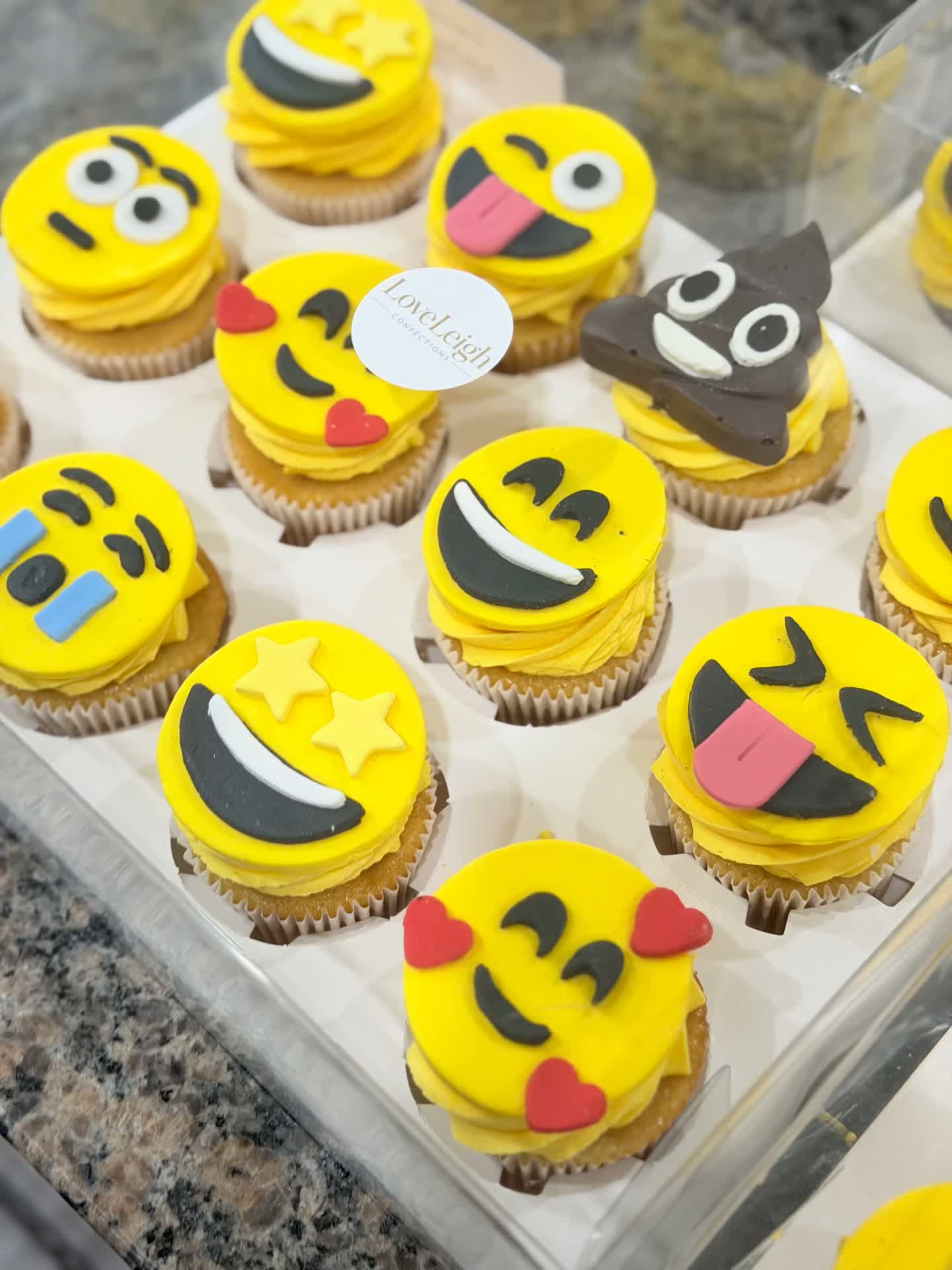 Emoji face cupcakes with yellow fondant toppers in a gift box