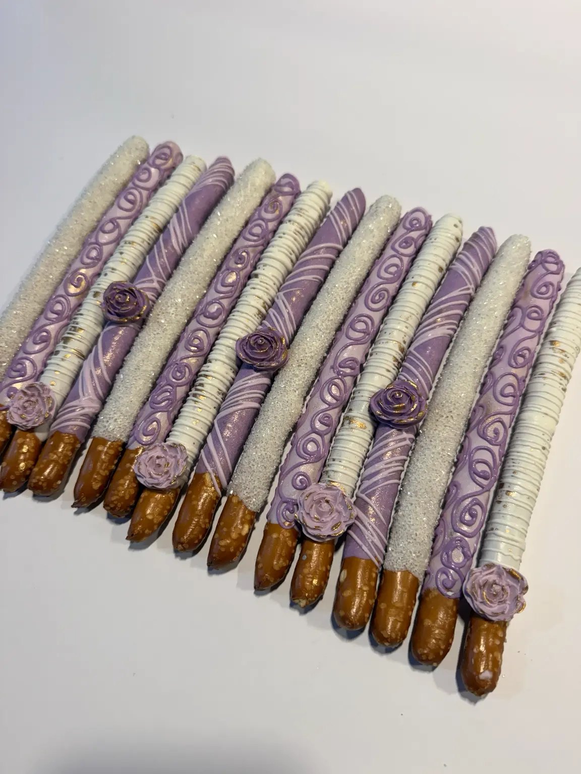 Lavender and white chocolate-covered pretzels with swirls, sparkle and sugar roses