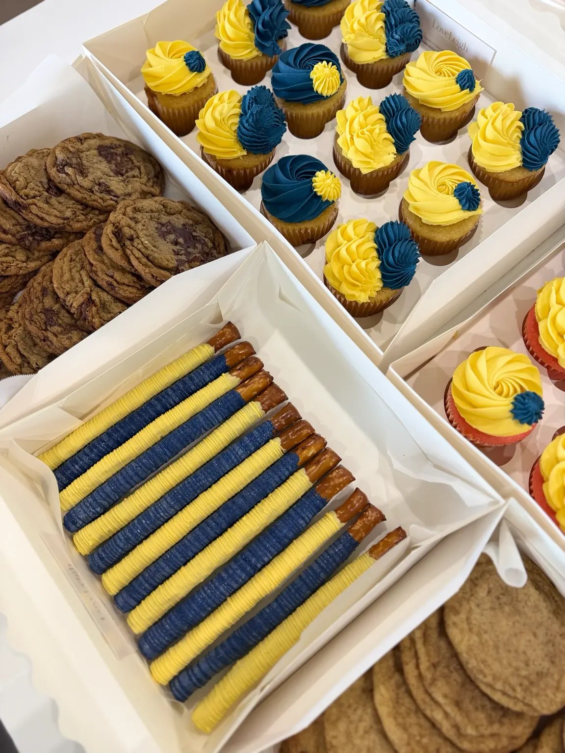 Navy and yellow coordinated cupcakes, chocolate-covered pretzels and cookies